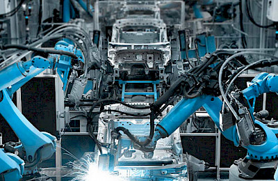 Blue industrial robot arms welding in a vehicle automation system.