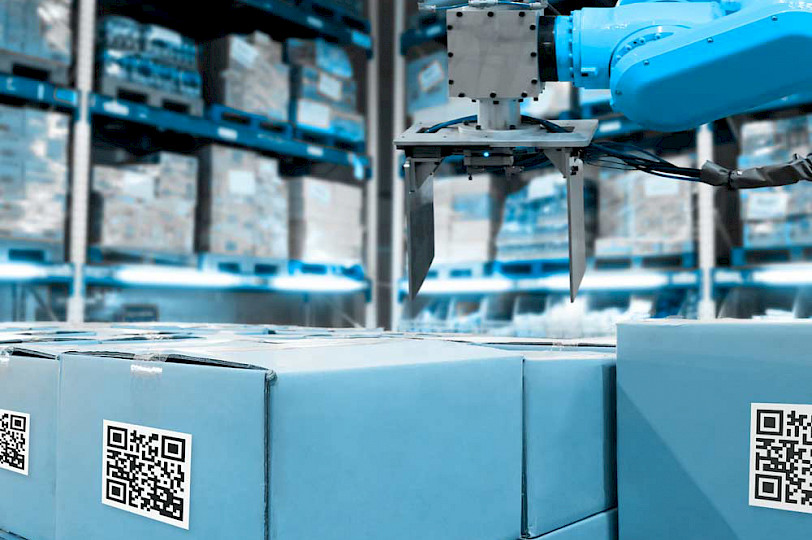 Blue shipping crates in a logistics hall with an industrial robot above them.