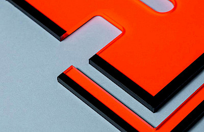 Orange acrylic panel with black edge on a gray surface.